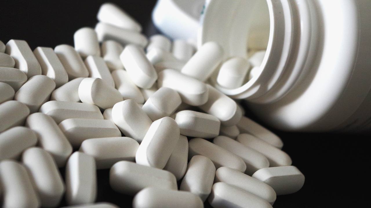 Comprimidos saindo de um frasco de medicamento